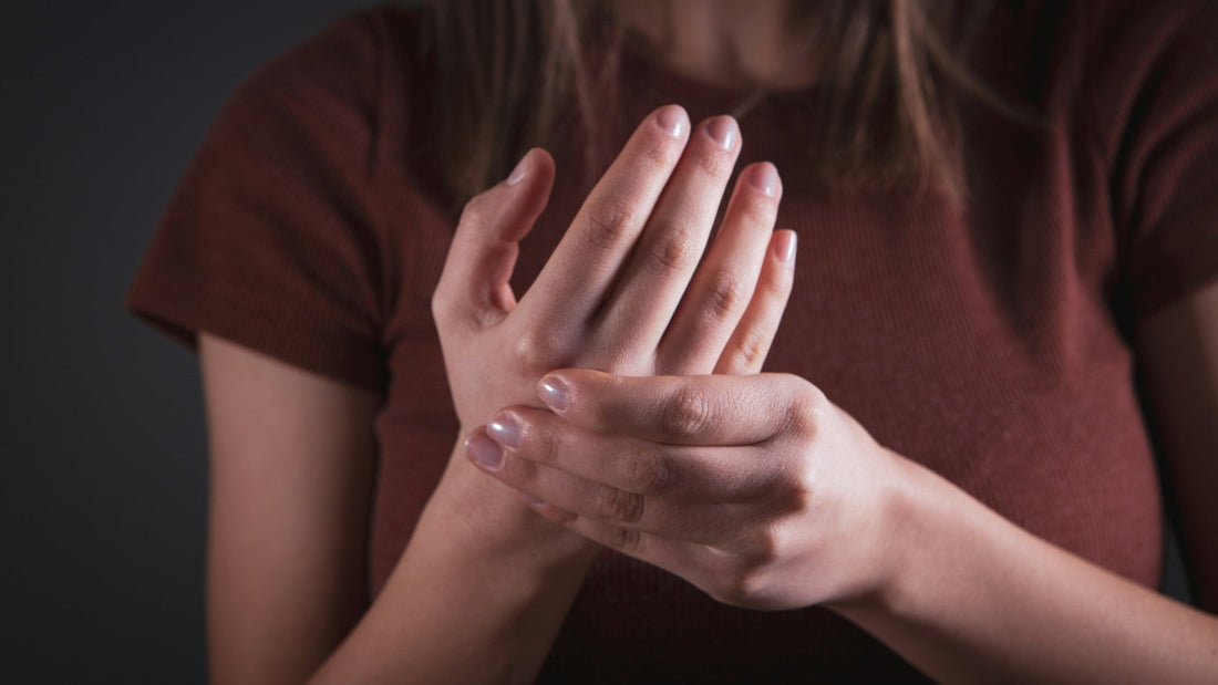 Woman rubbing a sore wrist and hand, a common sign of hand arthritis.