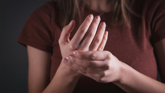 Woman rubbing a sore wrist and hand, a common sign of hand arthritis.