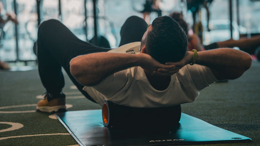 Man lying on a foam roller at the gym to ease muscle soreness after a workout