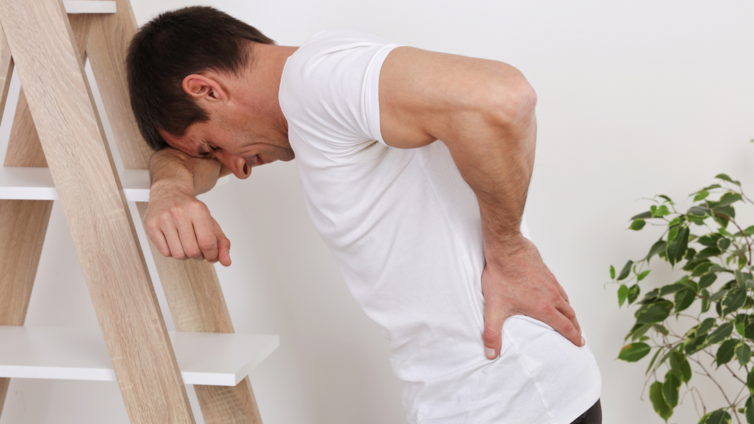 Man leaning on a ladder and holding his lower back in pain