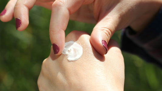 Fingers rubbing a dab of numbing cream into the back of a hand.