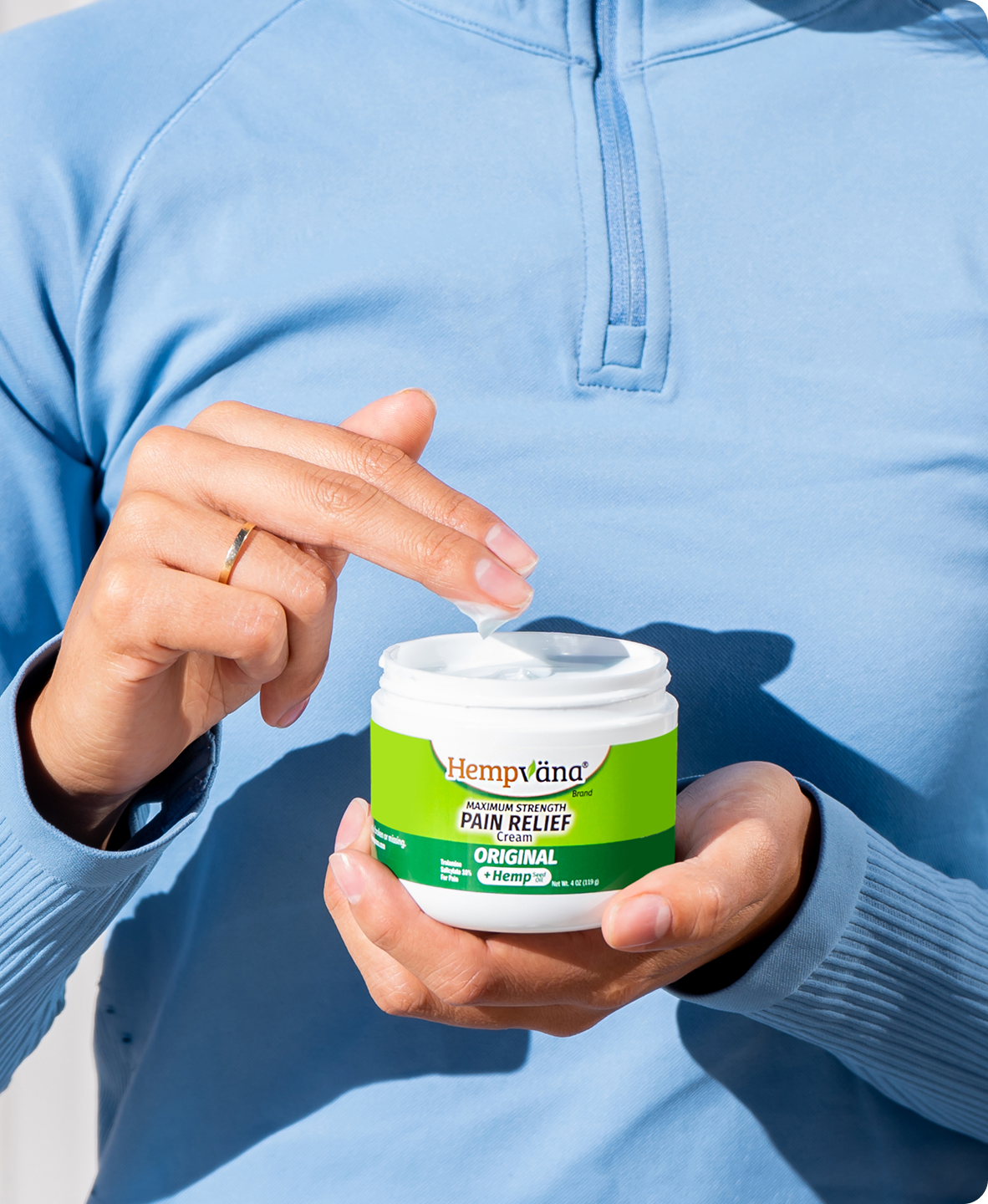 Person holding Hempväna Pain Relief Cream jar, demonstrating product usage
